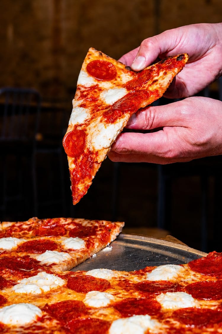 Hands lifting a triangle-cut pepperoni slice