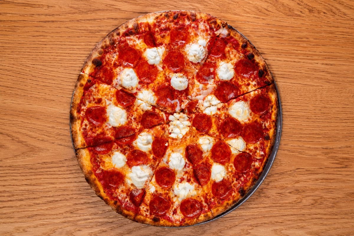 A whole pepperoni pie on a wooden table, overhead